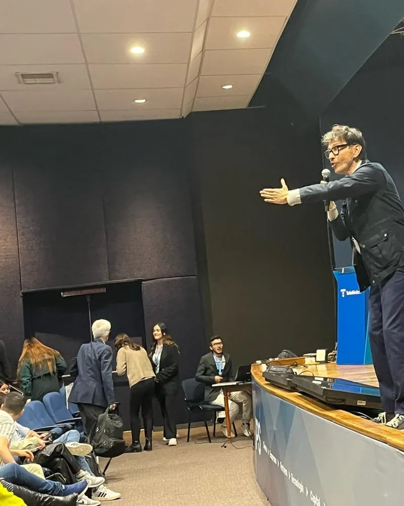Ponente de Achievers Lab con micrófono, dirigiéndose a un auditorio desde la tarima